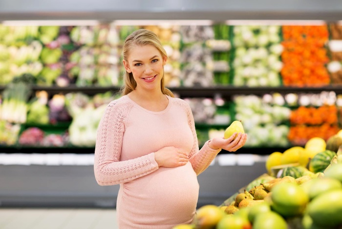 Беременная женщина выбирает грушу